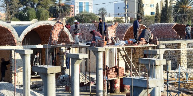 Tunisian builders work at the construction site of a new marketplace on December 15, 2015, in the impoverished central town of Sidi Bouzid, three days ahead of the fifth anniversary of the self-immolation of Mohamed Bouazizi, a young street vendor, which sparked the revolution that ousted a dictator and ignited the Arab Spring. Five years after triggering the Arab Spring, Tunisians doggedly pursue a democratic transition while other countries remain gripped by violence and repression. AFP PHOT