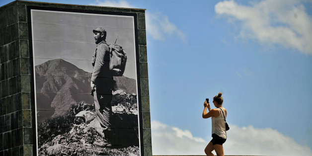 A tourist takes pictures of a poster depicting late Cuban leader Fidel Castro in Santiago de Cuba province on November 23, 2017.Cuba commemorates on November 25 the first anniversary of the death of Fidel Castro, focused on an electoral process that will imply a presidential change, in a framework of economic regression, hostility from the United States, and stagnation in its reforms. / AFP PHOTO / STR (Photo credit should read STR/AFP/Getty Images)