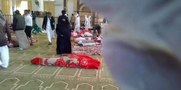 Egyptians gather around bodies following a gun and bombing attack at the Rawda mosque, roughly 40 kilometres west of the North Sinai capital of El-Arish, on November 24, 2017.A bomb explosion ripped through the mosque before gunmen opened fire on the worshippers gathered for weekly Friday prayers, officials said. / AFP PHOTO / STRINGER (Photo credit should read STRINGER/AFP/Getty Images)
