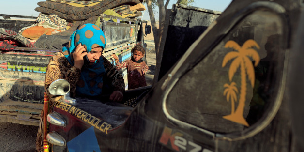 A woman who just fled Deir Ezzor talks on a mobile phone beside a truck with her belongings at a camp in Ain Issa, north of Raqqa, Syria August 12, 2017. REUTERS/Zohra Bensemra