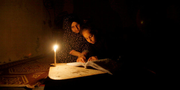 A Palestinian girl studies her lessons by a candlelight during power cut inside her family's house at Shati refugee camp in Gaza City April 25, 2017. Picture taken April 25, 2017. REUTERS/Mohammed Salem
