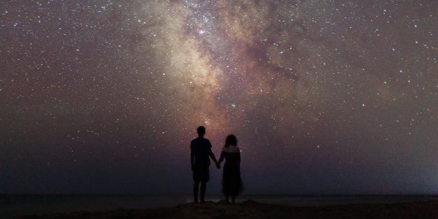 Young Caucasian couple walking near the sea at night under the starry sky