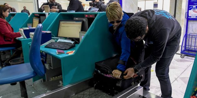 A Tunisian couple bound for London pack away their electronics in their luggage as they check-in for a flight at Tunis-Carthage International Airport on March 25, 2017.The United States this week announced a ban on all electronics larger than a standard smartphone on board direct flights out of eight countries across the Middle East, in effect from March 25, 2017. US officials would not specify how long the ban will last, but Emirates told AFP that it had been instructed to enforce the measures