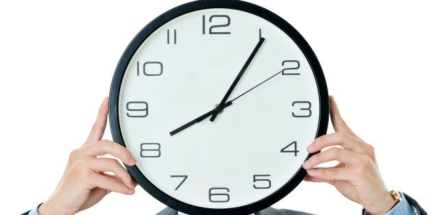Businessman holding clock against white background.