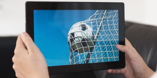 Concept of streaming live sports events. Soccer ball hits the net on a digital tablet.