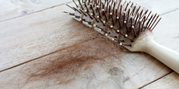 Hair loss, Close up of hairbrush with lost hair on wood table