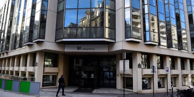 A pedestrian walks in front of the entrance to the headquarters of French cement producer Lafarge in Paris on November 14, 2017. A search is reported to be under way at Lafarge headquarters in Paris, which is suspected of indirectly funding jihadist groups in Syria, including the Islamic State (IS), said sources close to the survey and from the company. / AFP PHOTO / Martin BUREAU (Photo credit should read MARTIN BUREAU/AFP/Getty Images)