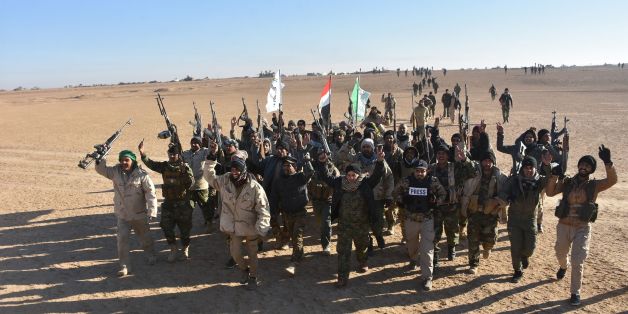 Members of the Hashed al-Shaabi (Popular Mobilisation) paramilitaries, celebrate after the Iraqi Prime Minister declared victory in the war against the Islamic State (IS) group, about 80 kilometres (about 50 miles) along the Iraqi-Syrian border west of the border town of al-Qaim on December 9, 2017. / AFP PHOTO / STRINGER (Photo credit should read STRINGER/AFP/Getty Images)