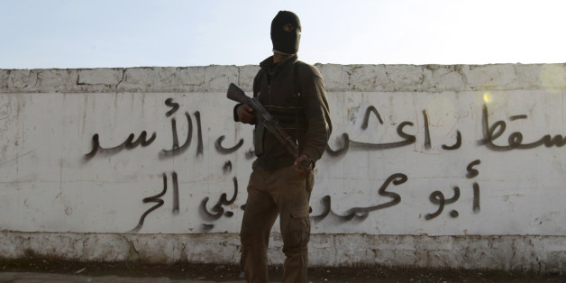 A Free Syrian Army fighter carries his weapon as he stands in front of graffiti that reads "Daesh (Islamic State of Iraq and the Levant ) down" at Masaken Hanano neighborhood in Aleppo January 7, 2014. Five days of heavy rebel infighting has shaken the ISIL, which lost its main base in the northern city of Aleppo to rival rebels on Wednesday, according to a monitoring group. Picture taken January 7, 2014. REUTERS/Jalal Alhalabi (SYRIA - Tags: POLITICS CIVIL UNREST CONFLICT MILITARY)