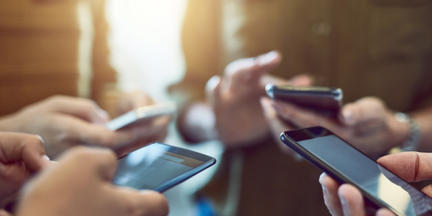 Cropped shot of a group of colleagues using their smart phones in synchronicity