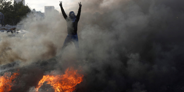 A masked Palestinian gestures in front of a burned barricade during a protest against U.S. President Donald Trump's decision to recognize Jerusalem as the capital of Israel, near the Jewish settlement of Beit El, near the West Bank city of Ramallah December 11, 2017. REUTERS/Goran Tomasevic TPX IMAGES OF THE DAY