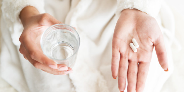 Woman holding a glass of water and pills, detail
