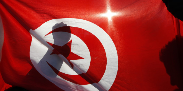 Tunisian people living in France demonstrate behind the Tunisian national flag during a protest in Marseille January 15, 2011. France called on Saturday for free elections as soon as possible in Tunisia and said it had taken steps to block suspicious movements of Tunisian assets in France. France, Tunisia's former colonial ruler, made the declaration in a statement released by President Nicolas Sarkozy's office after he held a meeting with several ministers in Paris. REUTERS/Jean-Paul Pelissier
