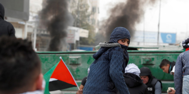 Palestinian protesters hide behind a barricade from Israeli forces during a protest against U.S. President Donald Trump's decision to recognize Jerusalem as the capital of Israel, near Qalandia checkpoint near the West Bank city of Ramallah, December 20, 2017 REUTERS/Goran Tomasevic