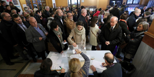 A woman casts her ballot as others wait to vote in Catalonia's regional elections at a polling station in Barcelona, Spain December 21, 2017. REUTERS/Albert Gea