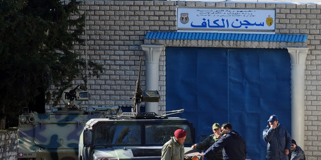 Soldiers speak in front of the prison on February 7, 2011 in Kef, northern Tunisia. Hundreds of angry protesters gather in front of the Kef police station after the announcement of the death of two individuals kept in their jails on February 7, 2011. The fire departement was mobilised to put out car fires. Four people were killed here when protesters set a police station ablaze amid fresh clashes Sunday. 'There's panic in the town. The district's security forces building is on fire,' said labou