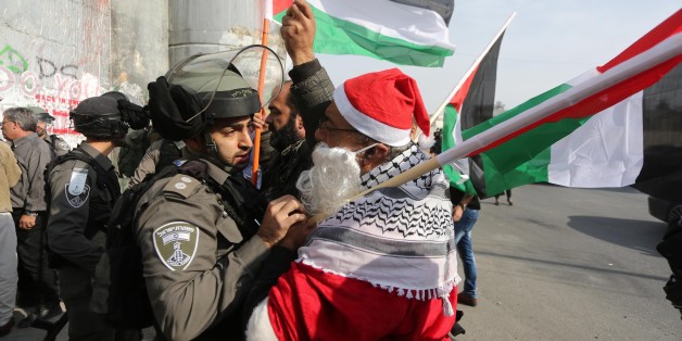 BETHLEHEM, WEST BANK - DECEMBER 23 : Israeli security forces intervene protesters dressed up as Santa-Claus during a protest against U.S. President Donald Trumps announcement to recognize Jerusalem as the capital of Israel and plans to relocate the U.S. Embassy from Tel Aviv to Jerusalem, in Bethlehem, West Bank on December 23, 2017. (Photo by Issam Rimawi /Anadolu Agency/Getty Images)