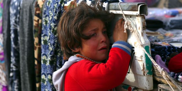 A displaced Syrian child, who was forced to leave his hometown by the war against the Islamic State (IS) group, is seen at the Ain Issa camp on December 18, 2017. As temperatures drop, tens of thousands of civilians forced out of their homes by Syria's war are spending yet another winter in flimsy plastic tents or abandoned half-finished buildings. And without heating, blankets and warm clothes, or access to proper medical care, even a simple cold can turn deadly. / AFP PHOTO / Delil souleima