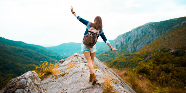 Young Hippie girl taking a walk on top of a mountain and enjoying the day. rear view