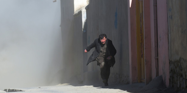 An Afghan man runs away as dust blows in the aftermath of the third blast at a Shiite cultural centre in Kabul on December 28, 2017.At least 40 people were killed and dozens more wounded in multiple blasts at a Shiite cultural centre in Kabul on December 28, officials said, in the latest deadly violence to hit the Afghan capital. / AFP PHOTO / SHAH MARAI (Photo credit should read SHAH MARAI/AFP/Getty Images)