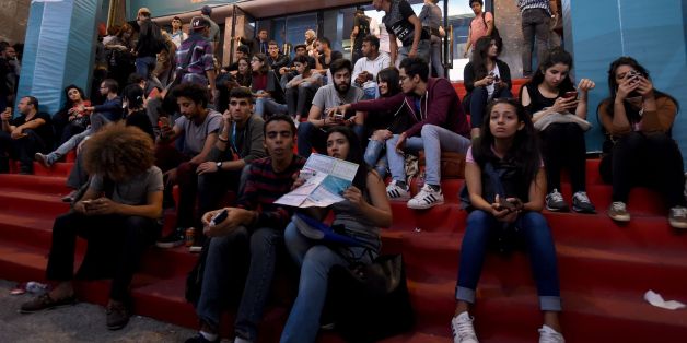Tunisian youths check the programme as they wait outside a movie theatre during the Carthage Film Festival in Tunis' seaside suburb of Carthage on November 2, 2016.The Carthage film festival will run from from October 28 to November 5. / AFP / FETHI BELAID (Photo credit should read FETHI BELAID/AFP/Getty Images)