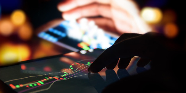 Silhouette finger on tablet with graph stock market trading screen with abstract blur smartphone bokeh background , stock market concept