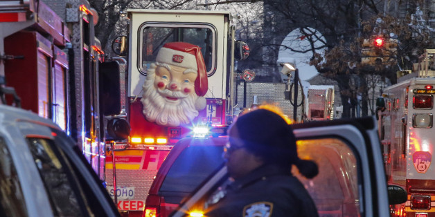 A Santa Claus figure is seen on the door of a fire truck as a New York Police Department (NYPD) officer works on the scene of an apartment fire on December 29, 2017 in the Bronx borough of New York City.Officials said Friday that the death toll from the fire has reached 12, including four children. / AFP PHOTO / KENA BETANCUR (Photo credit should read KENA BETANCUR/AFP/Getty Images)