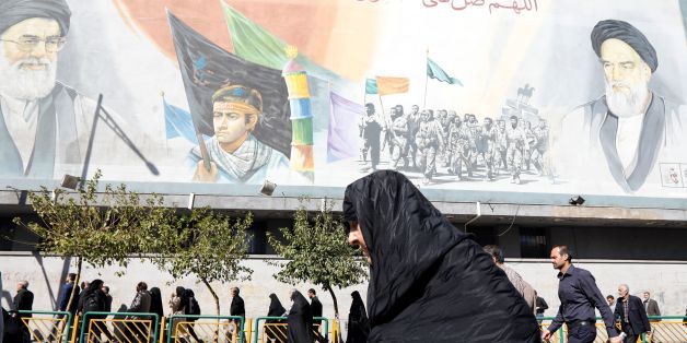 An Iranian woman walks past pictures of Iranian supreme leader Ayatollah Ali Khamenei (top L) and of late Iranian supreme leader Ayatollah Ruhollah Khomeini (top R), following the weekly Friday prayer in Tehran on October 13, 2017.President Donald Trump will unveil a more aggressive strategy to check Iran's growing power, but will stop short of withdrawing from a landmark nuclear deal or declaring the powerful Islamic Revolutionary Guard Corps a terrorist organization. During a White House speec