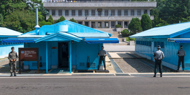 Jsa Within Dmz: UN soldiers close in front of blue buildings at North South Korean border with North Korean tourists in the background at Korean Demilitarized Zone, Panmunjom