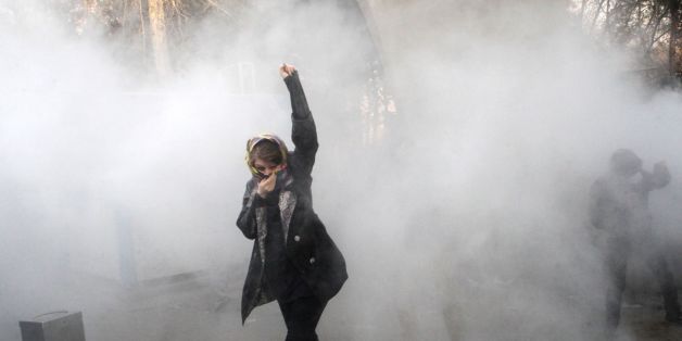 TOPSHOT - An Iranian woman raises her fist amid the smoke of tear gas at the University of Tehran during a protest driven by anger over economic problems, in the capital Tehran on December 30, 2017.Students protested in a third day of demonstrations sparked by anger over Iran's economic problems, videos on social media showed, but were outnumbered by counter-demonstrators. / AFP PHOTO / STR (Photo credit should read STR/AFP/Getty Images)