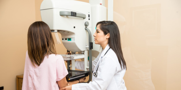 Pretty female doctor setting a patient in the correct position to get a mammogram in a clinic