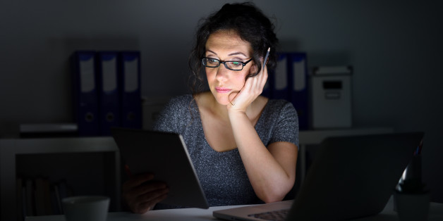 Woman in an office, using computer and working at night.