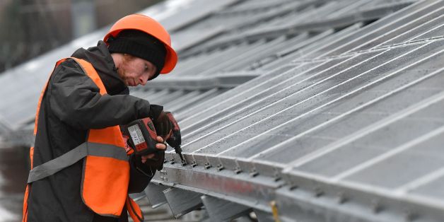 A worker installs photovoltaic panels on the new one-megawatt power plant next to the New Safe Confinement over the fourth block of the Chernobyl nuclear plant on December 12, 2017.At ground zero of Ukraine's Chernobyl tragedy, workers in orange vests are busy erecting hundreds of dark-coloured panels as the country gets ready to launch its first solar plant to revive the abandoned territory. The new one-megawatt power plant is located just a hundred metres from the new 'sarcophagus', a giant me