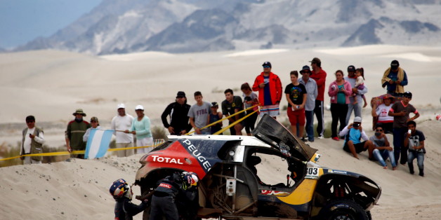 Carlos Sainz (L) of Spain and co-pilot Lucas Cruz work on a tire of their Peugeot during the 10th stage of the Dakar Rally 2016 near Fiambala, Argentina, January 13, 2016. REUTERS/Marcos Brindicci