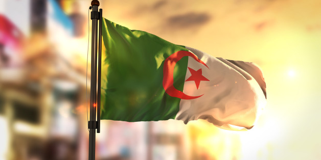 Algeria Flag Against City Blurred Background At Sunrise Backlight