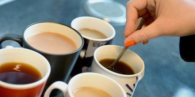 A woman stirs cups of tea and coffee, London