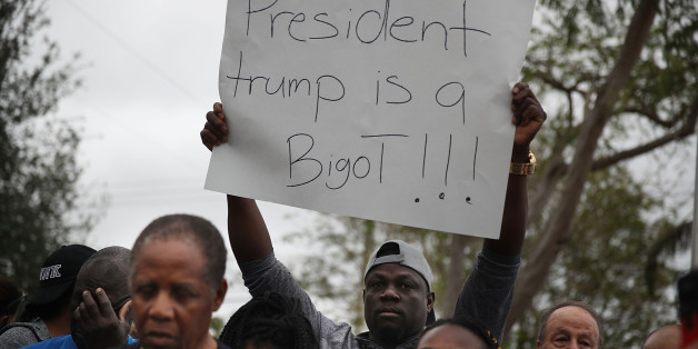 MIAMI, FL - JANUARY 12: Jorel Francois holds a sign that reads, 'President trump is a Bigot!!!' as he joins with others to mark the 8th anniversary of the massive earthquake in Haiti and to condemn President Donald Trump's reported statement about immigrants from Haiti, Africa and El Salvador on January 12, 2018 in Miami, Florida. President Trump is reported to have called those places 'shithole countries' whose inhabitants are not desirable for U.S. immigration. (Photo by Joe Raedle/Getty Imag