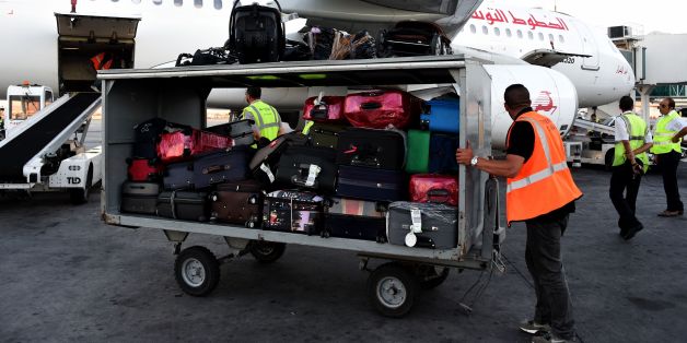 A picture taken on July 19, 2016 at Tunis-Carthage International Airport shows a labourer transporting luggage next to a Tunisair plane. / AFP PHOTO / FETHI BELAID (Photo credit should read FETHI BELAID/AFP/Getty Images)