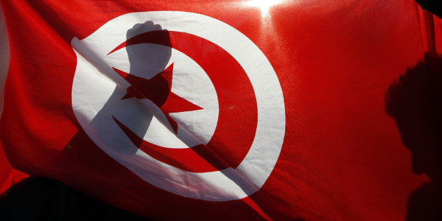 Tunisian people living in France demonstrate behind the Tunisian national flag during a protest in Marseille January 15, 2011. France called on Saturday for free elections as soon as possible in Tunisia and said it had taken steps to block suspicious movements of Tunisian assets in France. France, Tunisia's former colonial ruler, made the declaration in a statement released by President Nicolas Sarkozy's office after he held a meeting with several ministers in Paris. REUTERS/Jean-Paul Pelissier
