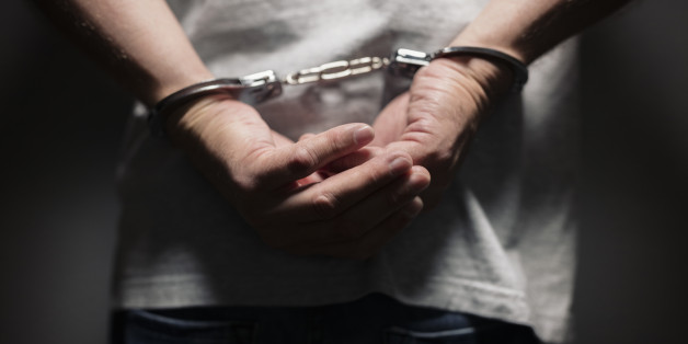 Arrested man in handcuffs with handcuffed hands behind back