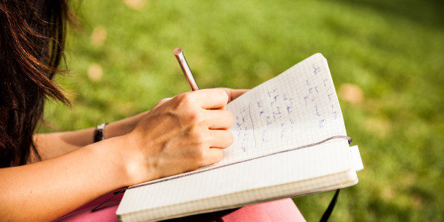 Young woman writing on diary while chilling at the park.