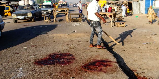 A man stands with his back to the blood stained scene of three suicide bomb blasts that left 13 people dead in Maiduguri, northeast Nigeria, on October 23, 2017.Three female suicide bombers killed 13 people and wounded 16 in the northeastern city of Maiduguri on ctober 22, 2017, security sources said.The first bomber detonated her explosive belt in front of a small restaurant in the capital of Borno state 'when people were buying their dinner,' a military source said on condition of anonymity. T