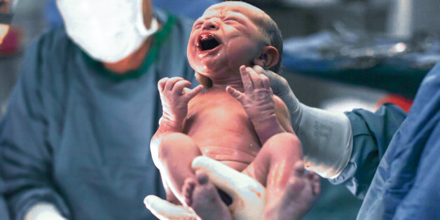 Doctors holding newborn baby boy.