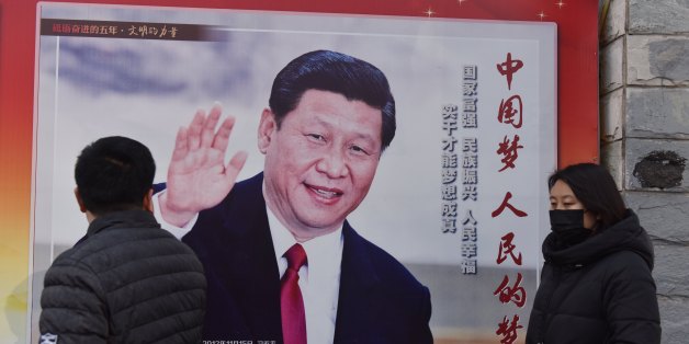 People walk past a poster of Chinese President Xi Jinping beside a street in Beijing on February 26, 2018.Xi Jinping's tightening grip on China had already earned the leader comparisons to Mao Zedong, but they came into even sharper focus after the party paved the way for him to assume the presidency indefinitely. / AFP PHOTO / GREG BAKER (Photo credit should read GREG BAKER/AFP/Getty Images)
