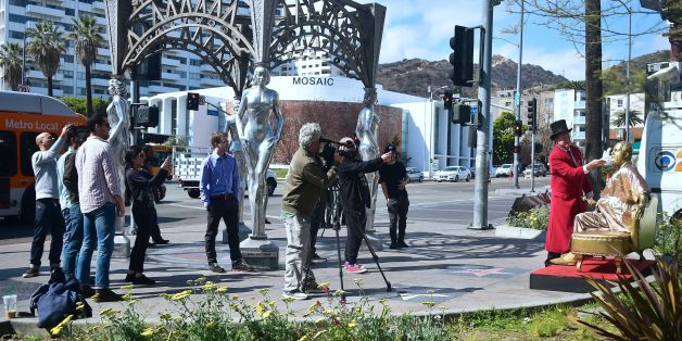 A crowd gathers to view a gold sculpture of Harvey Weinstein on his infamous casting couch holding an Oscar statue beside Elvis Presley's Walk of Fame Star in Hollywood, California on March 1, 2018, where artists Plastic Jesus and Joshua Monroe displayed their creation days before the 90th Oscars Awards on Sunday, March 4. / AFP PHOTO / Frederic J. BROWN (Photo credit should read FREDERIC J. BROWN/AFP/Getty Images)