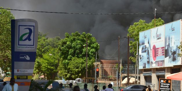 People watch as black smoke rises as the capital of Burkina Faso came under multiple attacks on March 2, 2018, targeting the French embassy, the French cultural centre and the country's military headquarters.Witnesses said five armed men got out of a car and opened fire on passersby before heading towards the embassy, in the centre of the city. Other witnesses said there was an explosion near the headquarters of the Burkinabe armed forces and the French cultural centre, which are located about a
