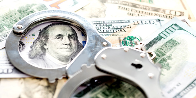 Handcuffs lying on american dollars, financial crime concept.