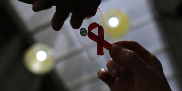 A nurse (L) hands out a red ribbon to a woman, to mark World Aids Day, at the entrance of Emilio Ribas Hospital, in Sao Paulo December 1, 2014. The world has finally reached "the beginning of the end" of the AIDS pandemic that has infected and killed millions in the past 30 years, according to a leading campaign group fighting HIV. United Nations data show that in 2013, 35 million people were living with HIV, 2.1 million people were newly infected with the virus and some 1.5 million people died of AIDS. By far the greatest part of the HIV/AIDS burden is in sub-Saharan Africa. REUTERS/Nacho Doce (BRAZIL - Tags: HEALTH SOCIETY)