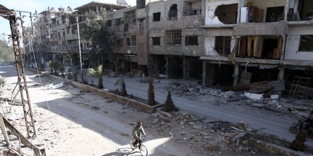 A Syrian man rides his bike amidst the destruction in the rebel-held town of Hamouria, in the besieged Eastern Ghouta region on the outskirts of the capital Damascus, on March 9, 2018. / AFP PHOTO / ABDULMONAM EASSA (Photo credit should read ABDULMONAM EASSA/AFP/Getty Images)