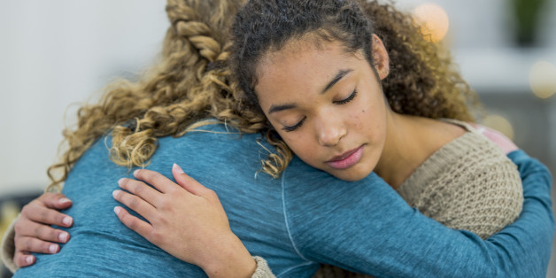 Two teenage friends are hanging out after school at home. One girl is upset and her best friend is comforting her. They are hugging.
